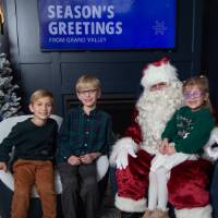 Three siblings smile with Santa